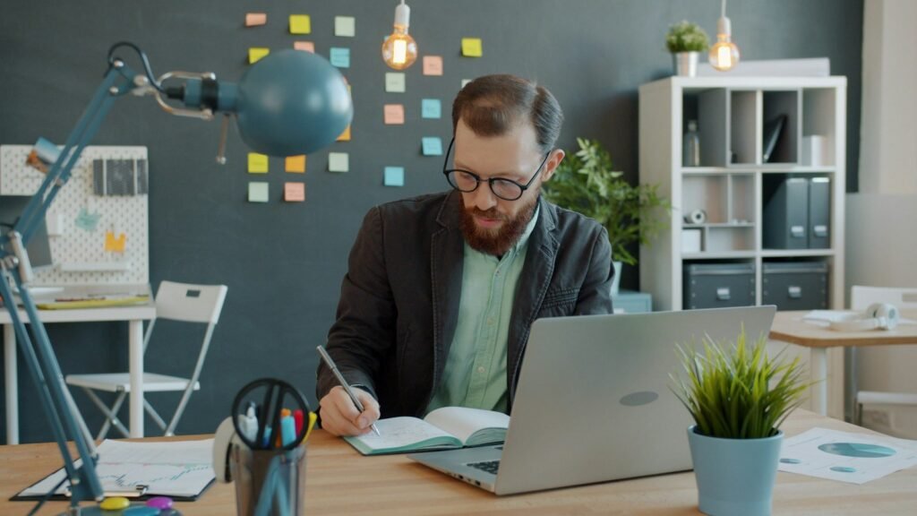 Professional writing notes and drafting content on a laptop at a desk